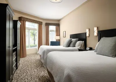 a hotel room with two beds and a television at West Inn & Suites in Carlsbad