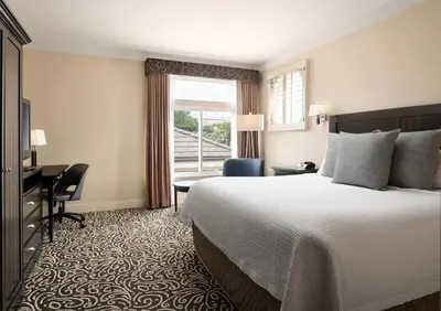 a hotel room with a bed and a desk and a window at West Inn & Suites in Carlsbad