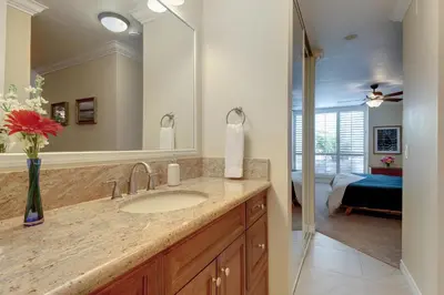 a bathroom with a sink and a mirror and a bedroom at North Coast Village Retreat B111 in Oceanside