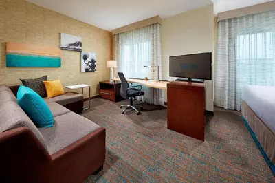 a hotel room with a couch and a desk and a television at Residence Inn by Marriott San Diego Chula Vista in Chula Vista