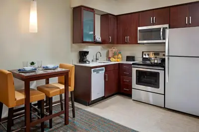 a kitchen with a table and a white refrigerator at Residence Inn by Marriott San Diego Chula Vista in Chula Vista