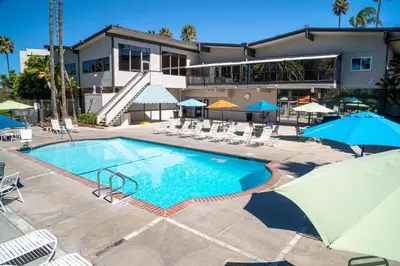 a swimming pool with chairs and umbrellas in front of a building at San Clemente Inn in San Clemente