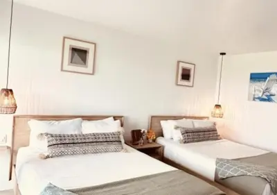 two beds in a room with white walls at Ocean Villa Inn in San Diego