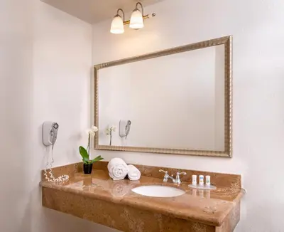 a bathroom with a sink and a large mirror at Beachfront Inn and Suites at Dana Point in Capistrano Beach