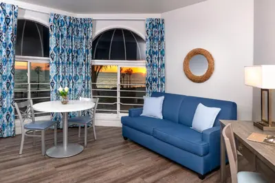 a living room with a blue couch and a table at Beachfront Inn and Suites at Dana Point in Capistrano Beach