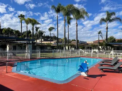 a large swimming pool with chairs and palm trees at Fallbrook Country Inn in Fallbrook
