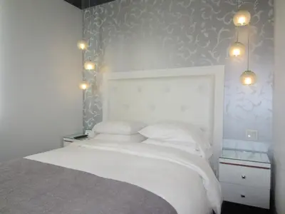a bedroom with a white bed with lights above it at La Pensione Hotel in San Diego