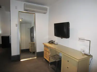a room with a desk and a television on a wall at La Pensione Hotel in San Diego