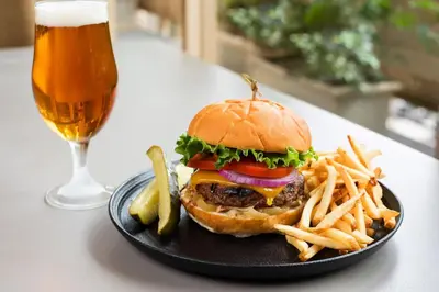 a black plate with a hamburger and fries and a glass of beer at Sheraton La Jolla in San Diego