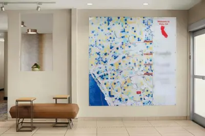 a large painting on a wall in a lobby with a bench at TownePlace Suites by Marriott San Diego Carlsbad / Vista in Vista