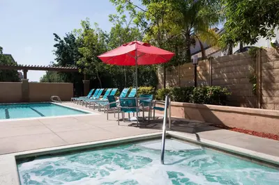 a pool with a red umbrella and chairs and a table with an umbrella at TownePlace Suites by Marriott San Diego Carlsbad / Vista in Vista