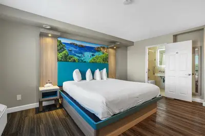 a bedroom with a large bed with a painting on the wall at Motel Mediteran in Escondido