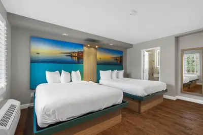 a hotel room with two beds and a painting on the wall at Motel Mediteran in Escondido