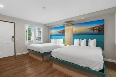two beds in a room with a painting on the wall at Motel Mediteran in Escondido
