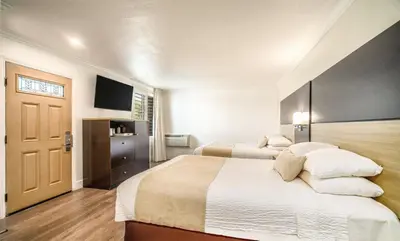 a bedroom with two beds and a flat screen tv at Little Inn By The Bay Newport Beach Hotel in Newport Beach