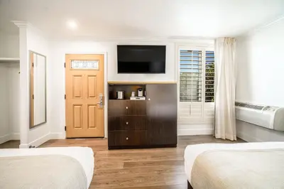 a bedroom with two beds and a flat screen tv at Little Inn By The Bay Newport Beach Hotel in Newport Beach