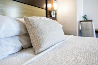 a bed with white pillows and a pillow on it at Little Inn By The Bay Newport Beach Hotel in Newport Beach