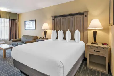 a hotel room with a large white bed and a couch at Best Western Americana Inn in San Ysidro, San Diego