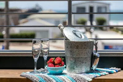 a table with two wine glasses and a bowl of strawberries at Ocean View 3 Bedrooms Condo, just steps from the park, pier & water! in Imperial Beach