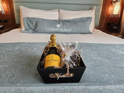a bottle of champagne in a box on a bed at Cormorant Boutique Hotel in San Diego