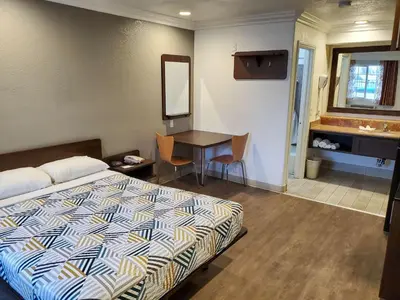 a bedroom with a bed and a desk with a mirror at Studio 6-National City, CA - Naval Base San Diego in National City