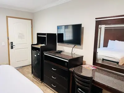 a hotel room with a bed and a desk with a television at Rodeway Inn National City San Diego South in National City