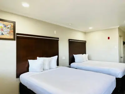 two beds in a hotel room with white sheets at Rodeway Inn Lemon Grove San Diego East in Lemon Grove