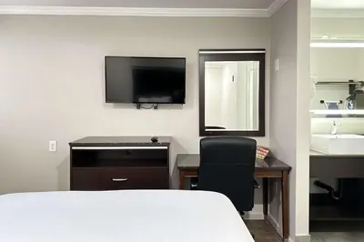 a hotel room with a bed and a desk and a television at Rodeway Inn Lemon Grove San Diego East in Lemon Grove