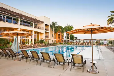 a pool with chairs and umbrellas next to a hotel at Grand Pacific Palisades Resort in Carlsbad