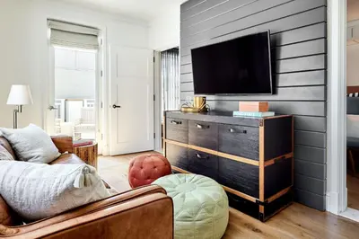 a living room with a tv on a wall at Lido House, Autograph Collection in Newport Beach