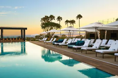 a pool with white lounge chairs and umbrellas at VEA Newport Beach, a Marriott Resort & Spa in Newport Beach