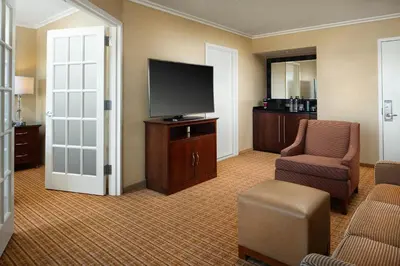a hotel room with a tv and a chair and a couch at Newport Beach Marriott Bayview in Newport Beach