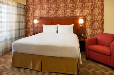 a bedroom with a bed and a red chair at Courtyard by Marriott San Diego Sorrento Valley in Sorrento