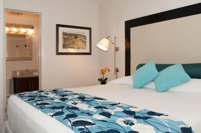 a bedroom with a large bed with blue pillows at Laguna Shores Studio Suites in Laguna Beach