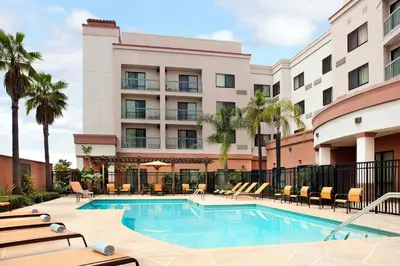 a pool at a hotel with chairs and palm trees at Courtyard Foothill Ranch Irvine East/Lake Forest in Foothill Ranch