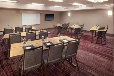 a conference room with tables and chairs and a whiteboard at Sonesta Select Laguna Hills Irvine Spectrum in Laguna Hills