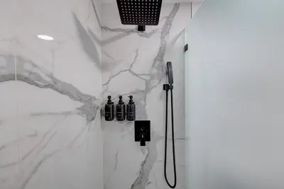 a bathroom with a shower with a white marble wall at Hotel Ash&9th in San Diego