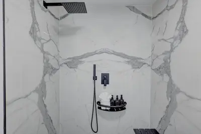 a shower in a bathroom with white marble walls at Hotel Ash&9th in San Diego