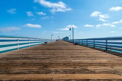 a wooden boardwalk leading to the ocean with lights at San Clemente Cove Resort in San Clemente