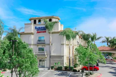 a hotel building with a red car parked in front of it at Fairfield Inn & Suites Temecula in Temecula