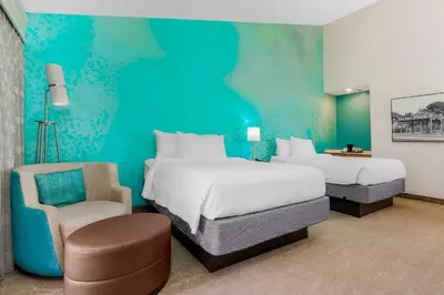 a hotel room with two beds and a chair at Courtyard by Marriott San Diego Del Mar/Solana Beach in Solana Beach