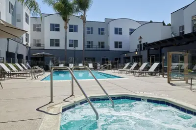 a swimming pool with chairs and a building in the background at Residence Inn San Diego Carlsbad in Carlsbad