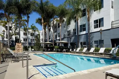 a swimming pool in a hotel with chairs and palm trees at Residence Inn San Diego Carlsbad in Carlsbad