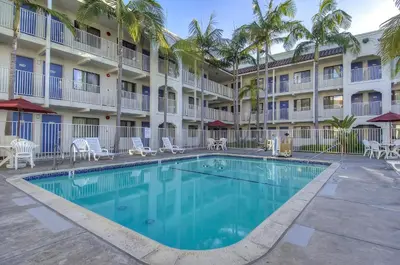 a swimming pool in front of a hotel with palm trees at Motel 6-Oceanside, CA in Oceanside