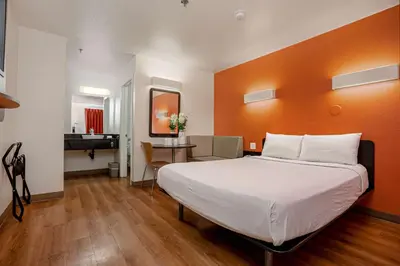 a bedroom with a large bed with an orange wall at Motel 6-Temecula, CA - Historic Old Town in Temecula