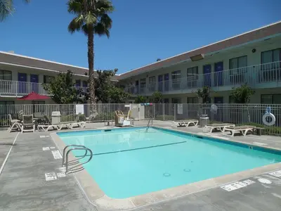 a swimming pool in front of a hotel with a palm tree at Motel 6-Temecula, CA - Historic Old Town in Temecula