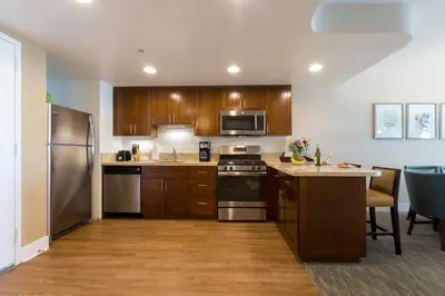 a kitchen with wooden cabinets and stainless steel appliances at Carlsbad Seapointe Resort in Carlsbad
