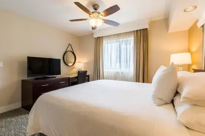 a bedroom with a white bed and a flat screen tv at Carlsbad Seapointe Resort in Carlsbad