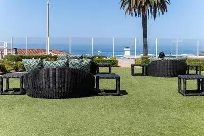 a group of wicker chairs and a palm tree at Carlsbad Inn Beach Resort in Carlsbad