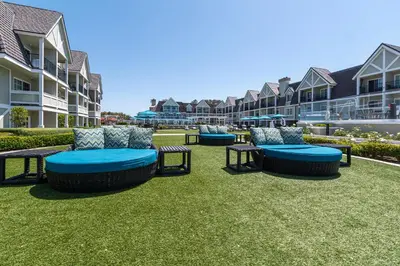 a group of chairs and tables on a lawn with buildings at Carlsbad Inn Beach Resort in Carlsbad